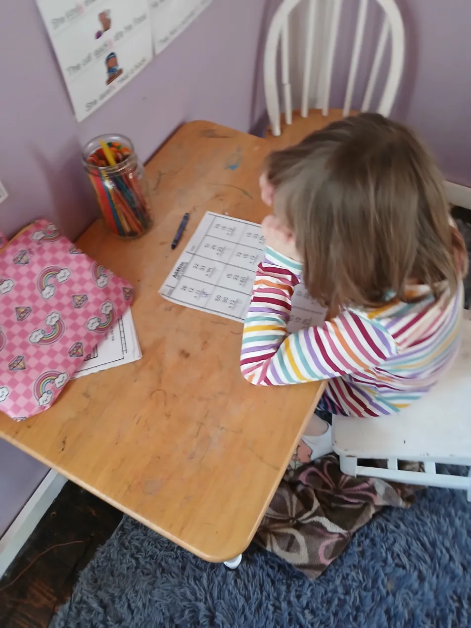 Child working independently at a small desk in a warm learning environment